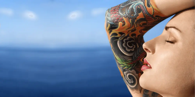 Woman with colorful half arm tattoo against a blue ocean background