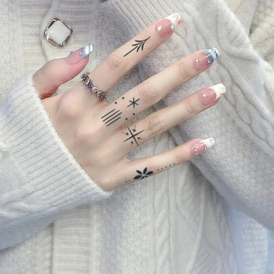 Hand with semi-permanent fingerprint tattoos and decorated nails, showcasing delicate and intricate designs for lasting artistry.