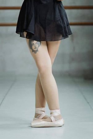 Ballet dancer showcasing a stylish thigh temporary tattoo with a unique design.