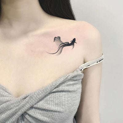 Minimalist koi tattoo on woman's shoulder, showcasing tranquil and harmonious design with meditative negative space.