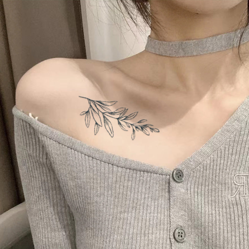 Elegant branch tattoo with falling green leaves design on shoulder, showcasing delicate lines and nature-inspired artistry.