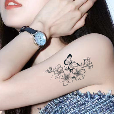 Woman's arm with butterfly and flower tattoo design, symbolizing freedom and beauty.